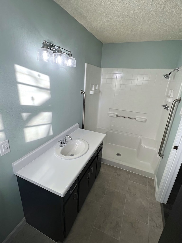 bathroom featuring vanity, tile patterned floors, a textured ceiling, and walk in shower