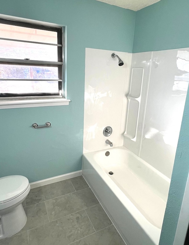 bathroom featuring tile patterned flooring, washtub / shower combination, and toilet