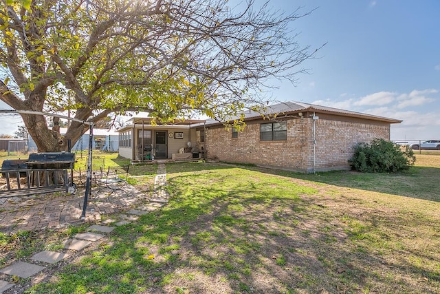 rear view of property featuring a yard, a sunroom, and a patio