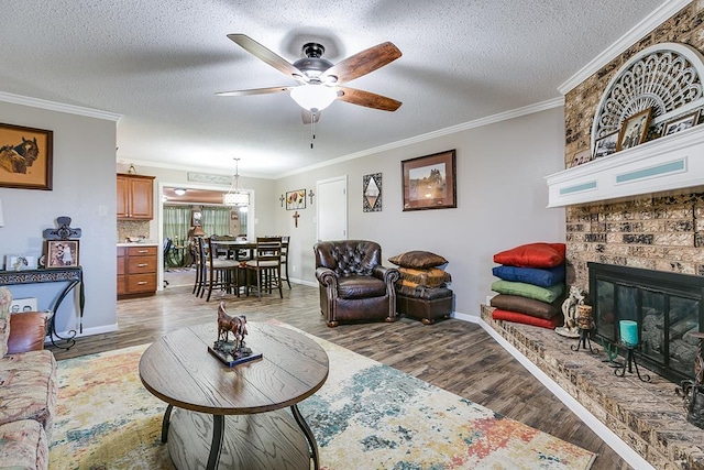 living room featuring ceiling fan, ornamental molding, a textured ceiling, dark hardwood / wood-style flooring, and a brick fireplace