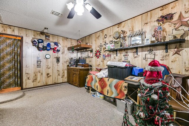 misc room featuring carpet flooring, a textured ceiling, and wood walls