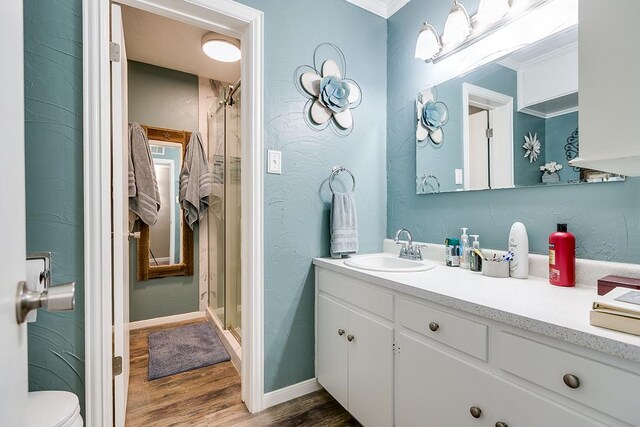 bathroom featuring toilet, an enclosed shower, crown molding, vanity, and hardwood / wood-style flooring