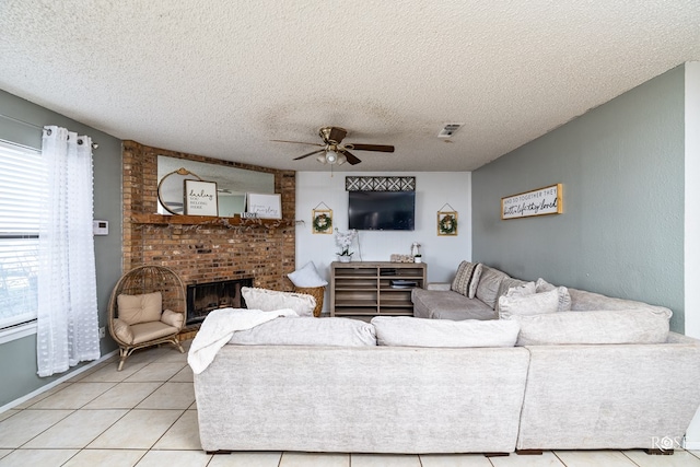 living area with visible vents, a ceiling fan, a textured ceiling, a fireplace, and light tile patterned flooring