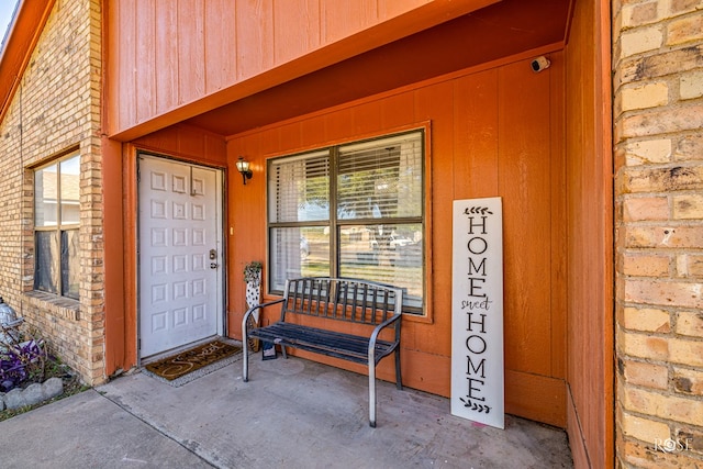 entrance to property with covered porch and brick siding