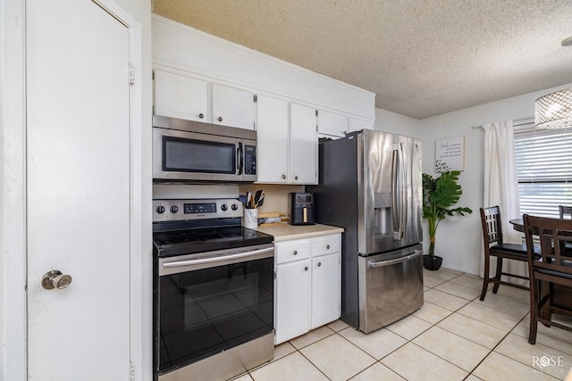 kitchen with light tile patterned floors, light countertops, appliances with stainless steel finishes, white cabinets, and a textured ceiling