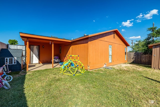 rear view of house with a lawn, a patio area, and fence