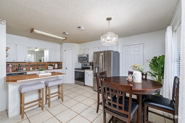 kitchen with appliances with stainless steel finishes, white cabinets, visible vents, and a peninsula