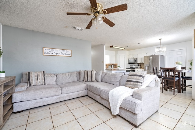 living room featuring visible vents, ceiling fan, a textured ceiling, and light tile patterned floors