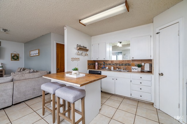 kitchen with open floor plan, white cabinets, a kitchen breakfast bar, and light tile patterned floors