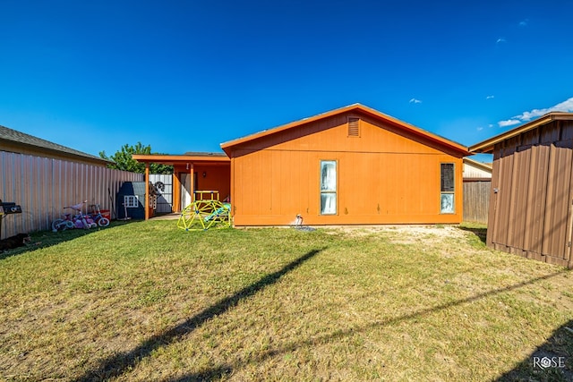 back of house with fence, an outbuilding, and a yard