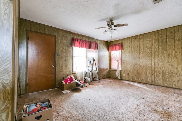 game room with ceiling fan, carpet flooring, and wood walls