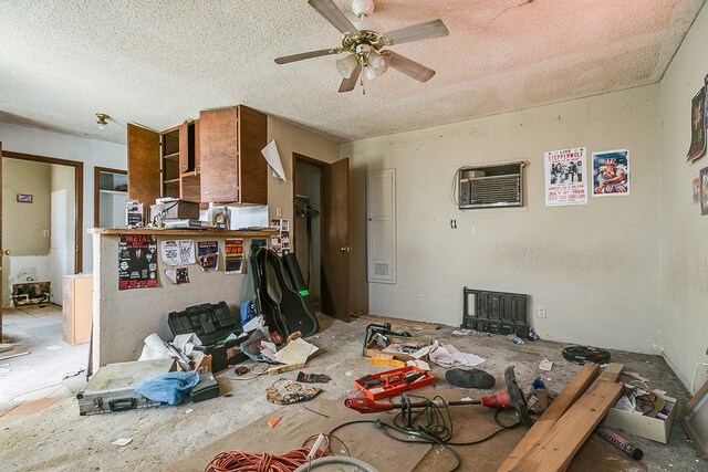 interior space featuring ceiling fan, a wall mounted air conditioner, and a textured ceiling