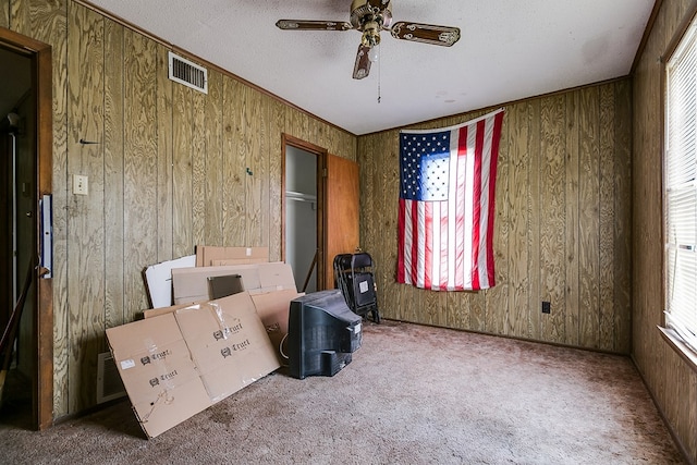 interior space with ceiling fan, wooden walls, and a textured ceiling