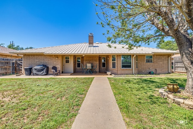 1729 Parkview Dr, San Angelo, TX 76904 - rear view of property with brick siding, a chimney, a patio area, and a metal roof
