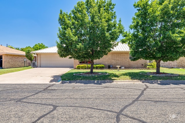 1729 Parkview Dr, San Angelo, TX 76904 - obstructed view of property featuring concrete driveway, brick siding, a metal roof, an attached garage, and a front lawn