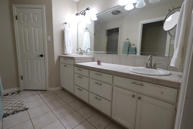 710 Penhurst Ct, San Angelo, TX 76901 - bathroom featuring double vanity, tile patterned flooring, baseboards, and a shower with shower door