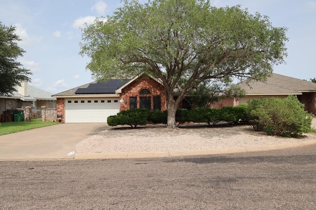 710 Penhurst Ct, San Angelo, TX 76901 - view of front facade with concrete driveway, solar panels, a garage, and brick siding