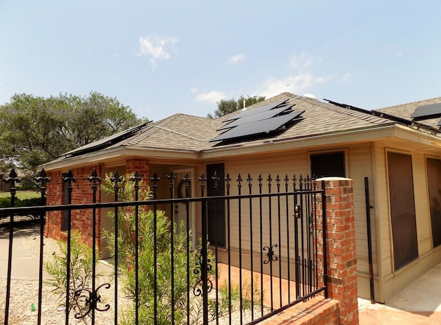 710 Penhurst Ct, San Angelo, TX 76901 - view of property exterior featuring a shingled roof, solar panels, and brick siding