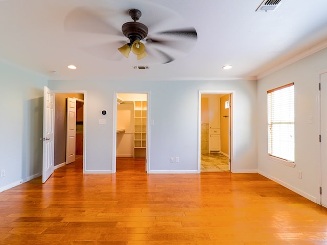 unfurnished bedroom with ensuite bath, ceiling fan, ornamental molding, a spacious closet, and a closet