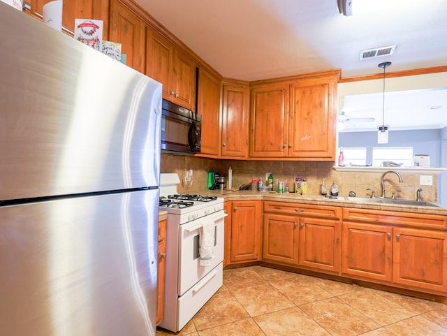 kitchen with sink, stainless steel fridge, decorative backsplash, hanging light fixtures, and gas range gas stove