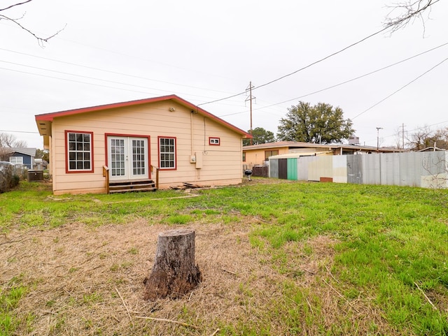 back of property featuring french doors and a lawn