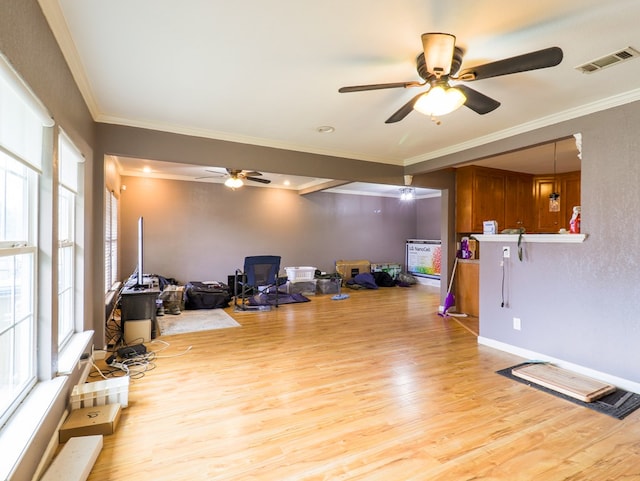 interior space with ceiling fan, ornamental molding, light hardwood / wood-style floors, and a wood stove