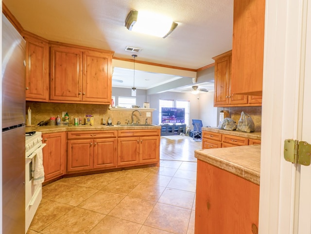 kitchen with decorative light fixtures, tasteful backsplash, sink, stainless steel fridge, and white gas range oven