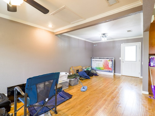 interior space with wood-type flooring, ornamental molding, and ceiling fan