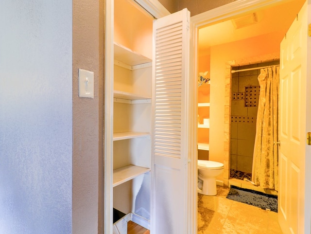 bathroom featuring toilet and curtained shower