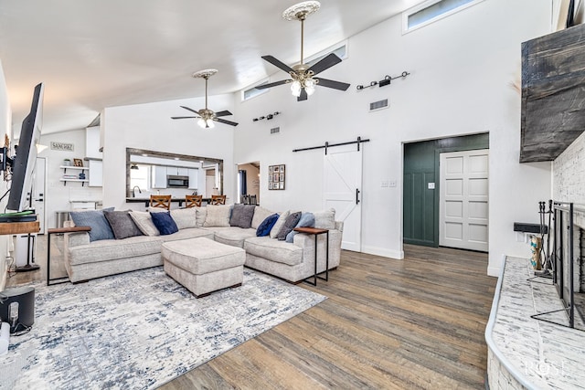 3610 Southland Blvd, San Angelo, TX 76904 - living area with a barn door, a ceiling fan, wood finished floors, high vaulted ceiling, and a fireplace with raised hearth