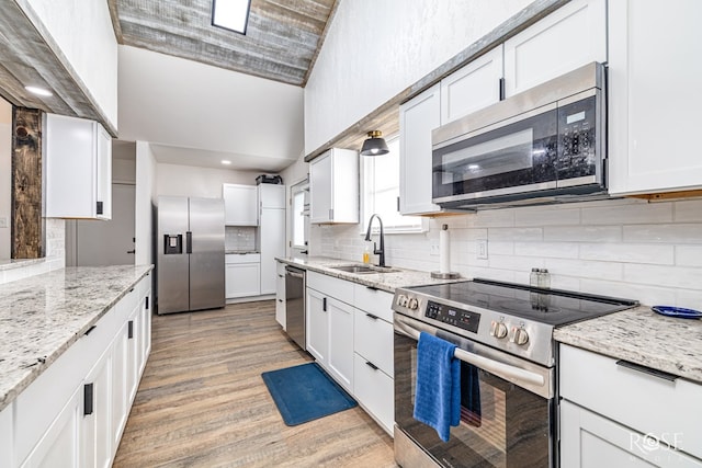 3610 Southland Blvd, San Angelo, TX 76904 - kitchen with stainless steel appliances, a sink, light wood-style floors, backsplash, and high vaulted ceiling
