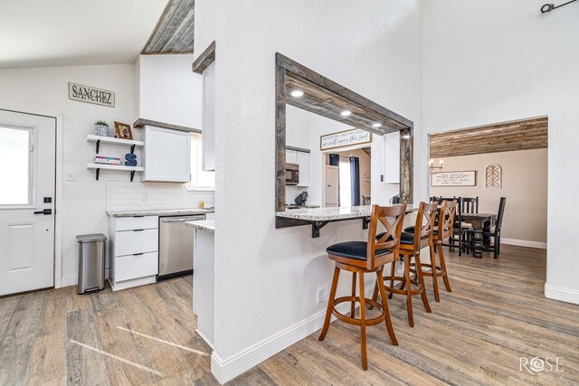 3610 Southland Blvd, San Angelo, TX 76904 - kitchen with appliances with stainless steel finishes, light wood finished floors, white cabinetry, a breakfast bar, and open shelves