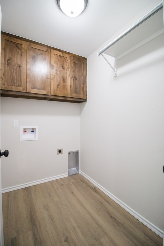 laundry area with electric dryer hookup, hookup for a washing machine, light hardwood / wood-style flooring, and cabinets