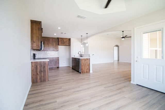 kitchen featuring sink, ceiling fan, a kitchen island with sink, backsplash, and decorative light fixtures