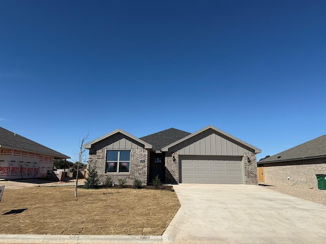 view of front of house with an attached garage, driveway, board and batten siding, and brick siding