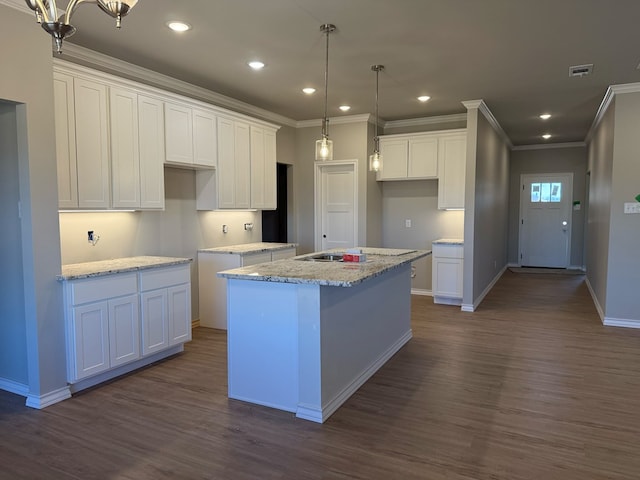 kitchen featuring dark wood-style flooring, an island with sink, visible vents, and white cabinetry