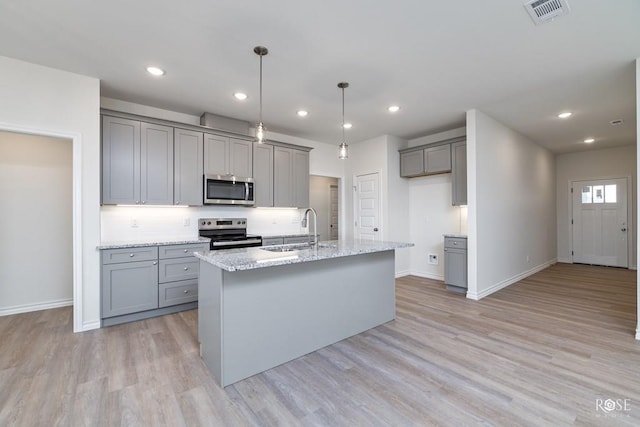 kitchen featuring appliances with stainless steel finishes, sink, gray cabinetry, hanging light fixtures, and light stone countertops