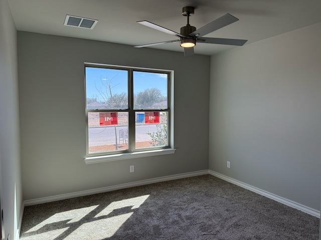 carpeted spare room featuring ceiling fan, visible vents, and baseboards