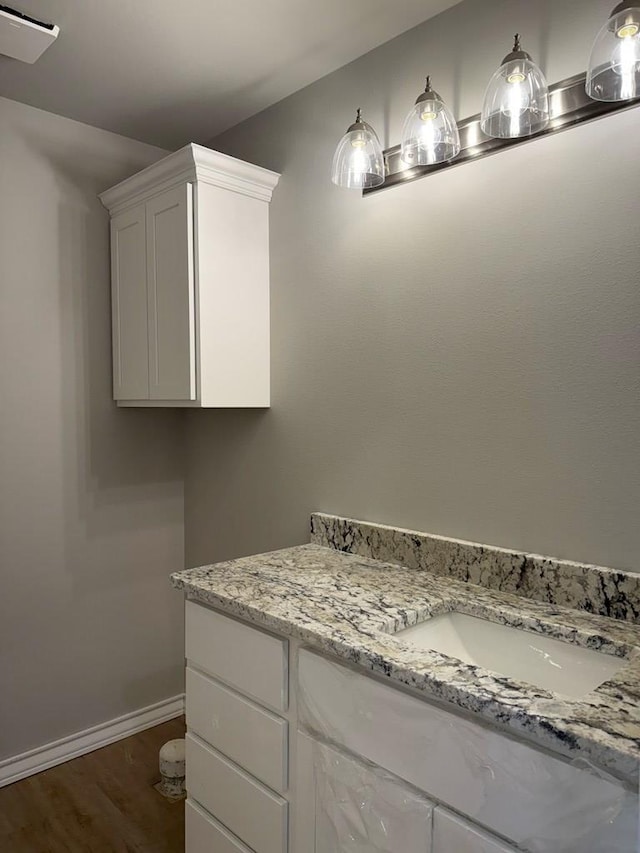 bathroom with baseboards, wood finished floors, and vanity