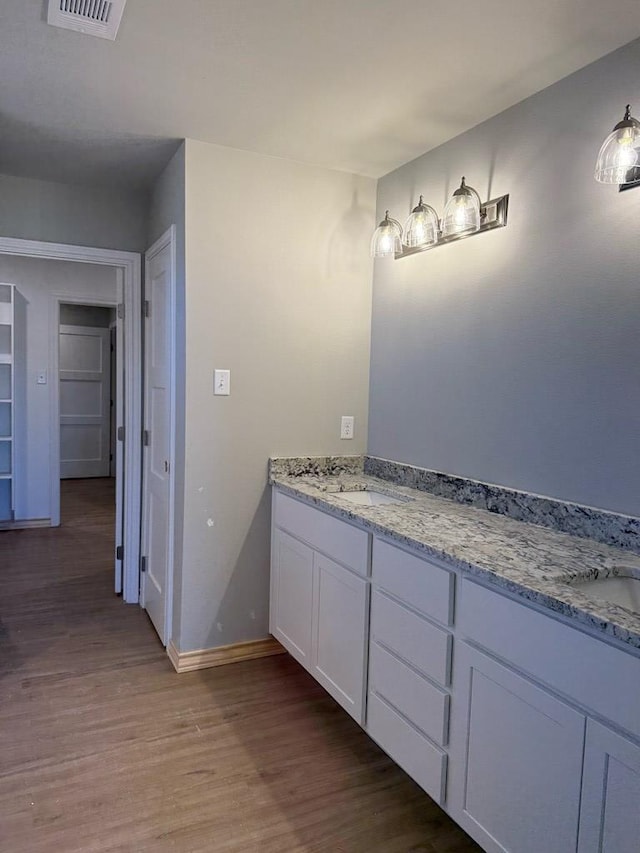 bathroom with a sink, visible vents, baseboards, and wood finished floors