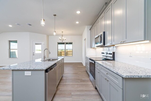 kitchen with sink, gray cabinetry, hanging light fixtures, an island with sink, and stainless steel appliances