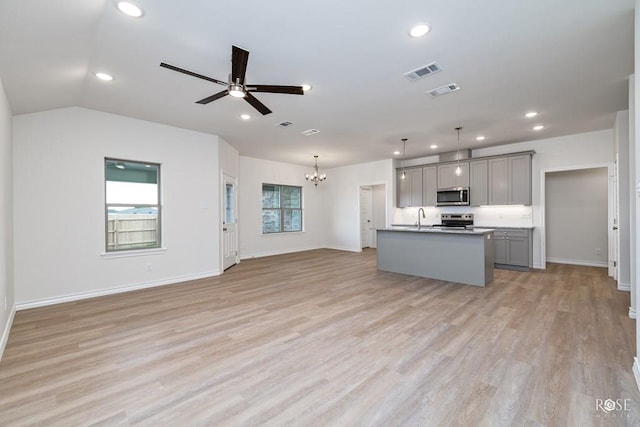 kitchen with gray cabinets, pendant lighting, a kitchen island with sink, stainless steel appliances, and light hardwood / wood-style flooring