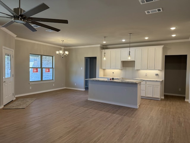 kitchen with a center island, white cabinets, visible vents, and wood finished floors