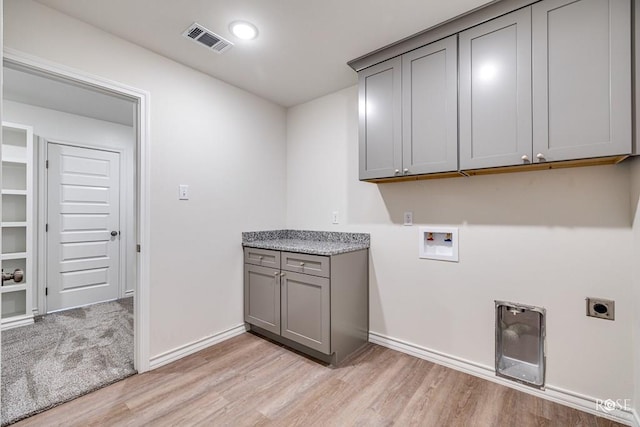 clothes washing area with washer hookup, visible vents, light wood-style floors, cabinet space, and electric dryer hookup