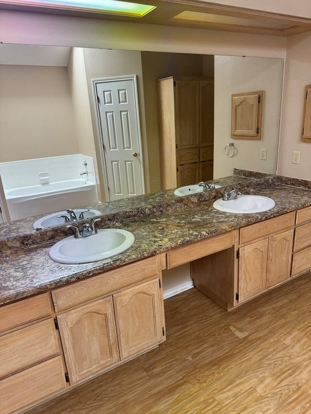 bathroom with a bath, vanity, and hardwood / wood-style floors