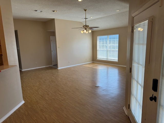 unfurnished room with ceiling fan, vaulted ceiling, hardwood / wood-style floors, and a textured ceiling