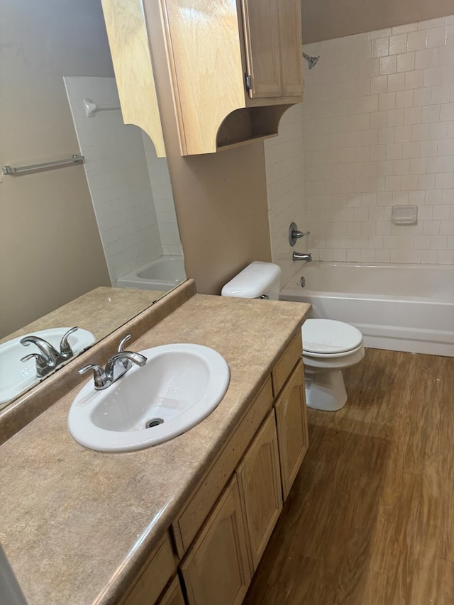 full bathroom featuring vanity, tiled shower / bath, hardwood / wood-style flooring, and toilet