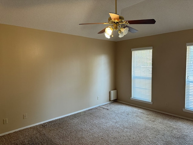 empty room featuring a wealth of natural light, ceiling fan, and carpet