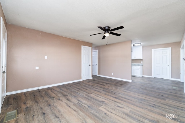 unfurnished living room with ceiling fan, dark hardwood / wood-style floors, and a textured ceiling