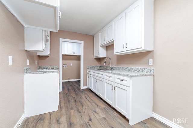 kitchen with white cabinetry, sink, light stone counters, and dark wood-type flooring